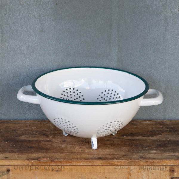 A generous sized colander made from Romanian enamelware, in white with a blue rim. Internal rim diameter 24cm and height 13cm, with side handles and three feet. An ideal size for picking and washing garden produce, or draining rice or pasta.