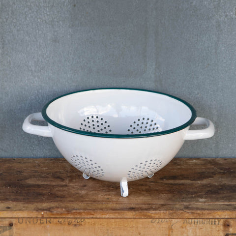 A generous sized colander made from Romanian enamelware, in white with a blue rim. Internal rim diameter 24cm and height 13cm, with side handles and three feet. An ideal size for picking and washing garden produce, or draining rice or pasta.