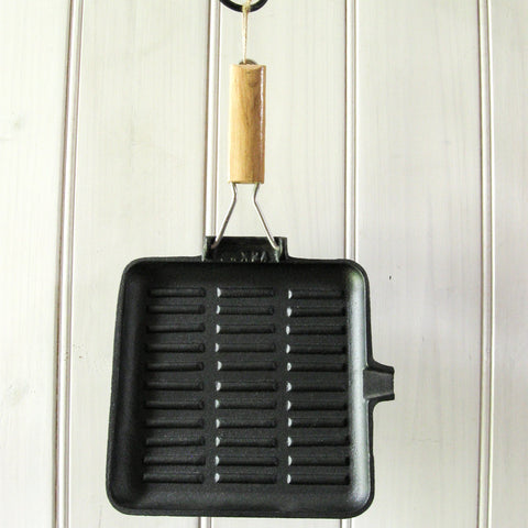 Sear meat in the kitchen or over the campfire with a pre-seasoned cast iron skillet, square 24cm x 24cm, square large 28cm x 28cm, or oblong 21cm x 35cm, with folding timber handle. 