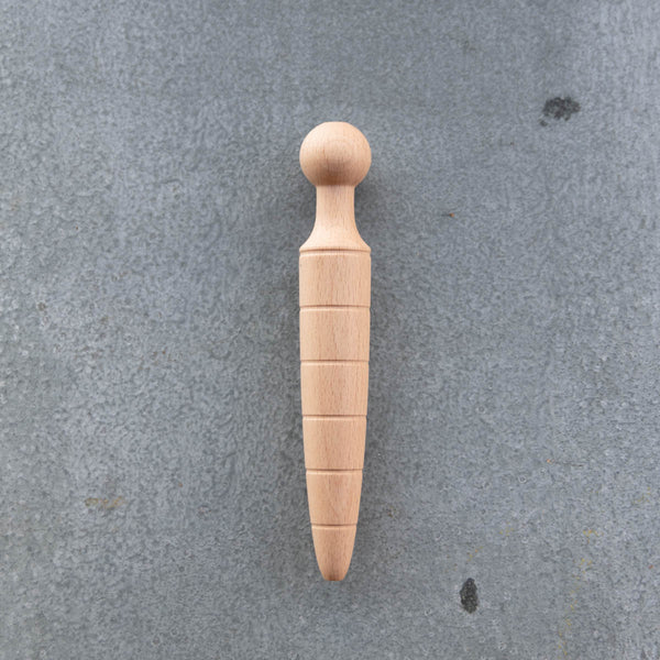 A traditional oak wooden dibber used for making neat holes in a garden bed for planting seeds to a uniform depth.