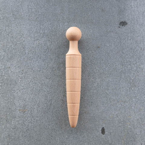 A traditional oak wooden dibber used for making neat holes in a garden bed for planting seeds to a uniform depth.
