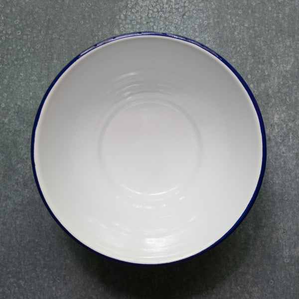 Falcon enamel deep serving bowl, here in white with a blue rim. Use the serving bowl for sharing vegetables, salad, rice or pasta dishes.
