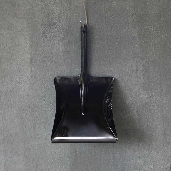 A simple dust pan made of one piece of moulded metal in black, with a removable rubber lip.