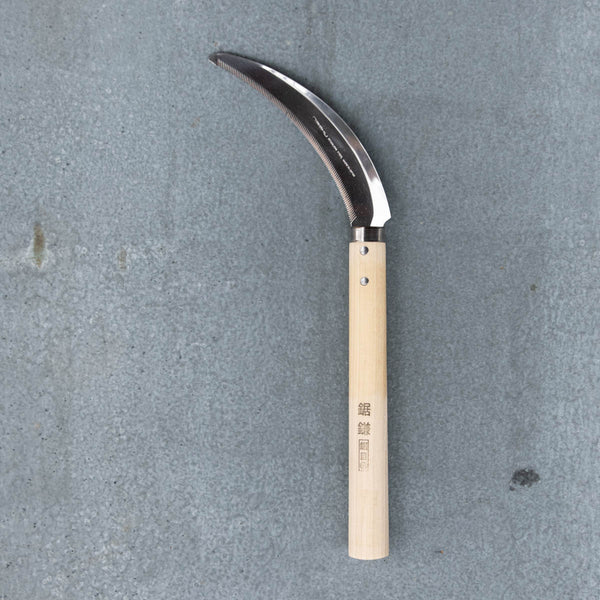 Nisaku Nokome Tooth Sickle with a stainless steel 15cm toothed blade on the inner curve and sharp, smooth blade on the outer curve and a 22cm timber handle.