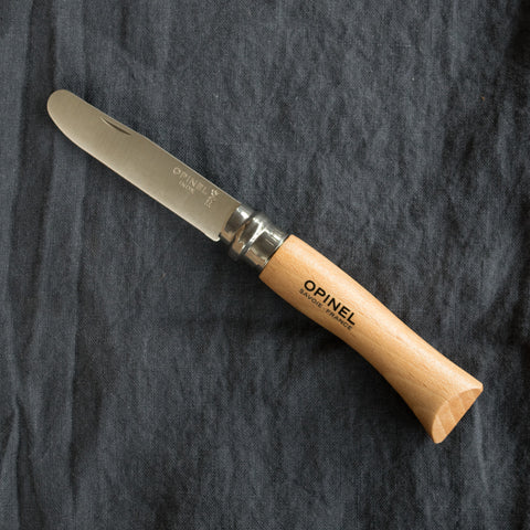 An Opinel No. 7 stainless steel knife ("My first Opinel") with a rounded steel safety tip blade and varnished wood handle, ideal for bush walks, camping, picnics, odd jobs, carving wood, and cutting string.