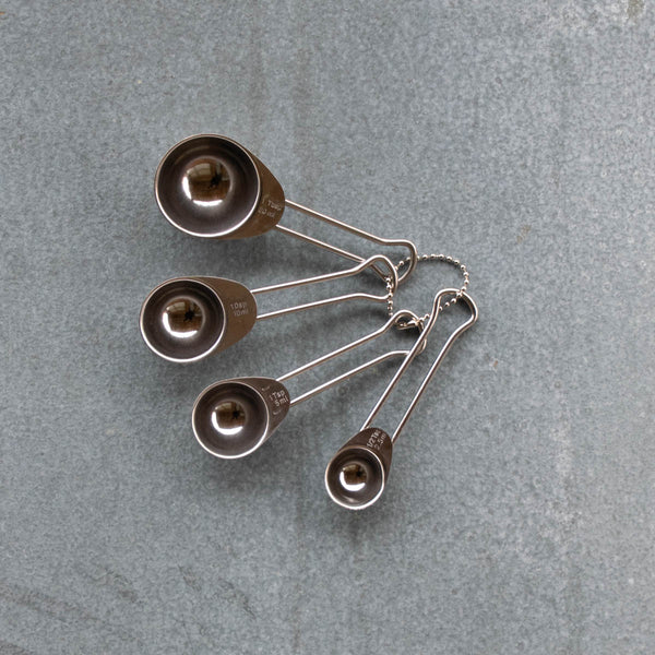 Stainless steel measuring spoons, an essential for every kitchen. Marked and sized as follows: 1 Tbsp 20ml; 1Dsp 10ml; 1 Tsp 5ml; 1/2 Tsp 2.5ml. They are light, hardy, and strung together so they are easy to store, and find.